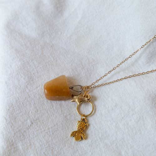 Gold necklace with a small pendant on a white fabric background