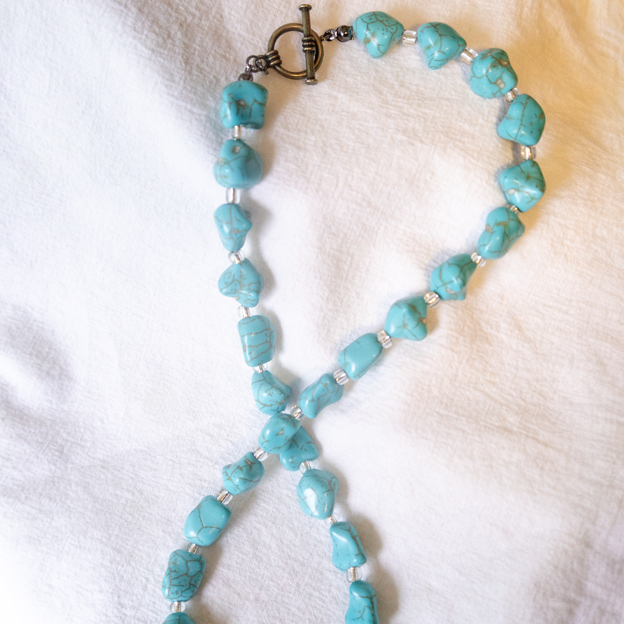 Turquoise beaded necklace on a white fabric background