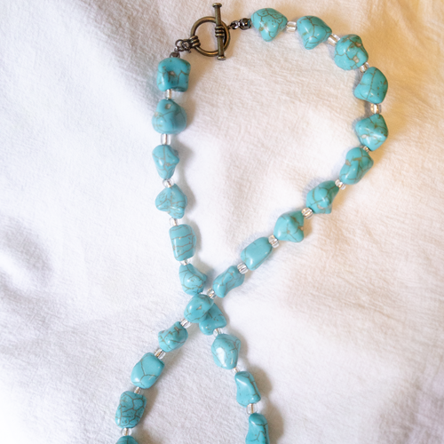 Turquoise beaded necklace on a white fabric background
