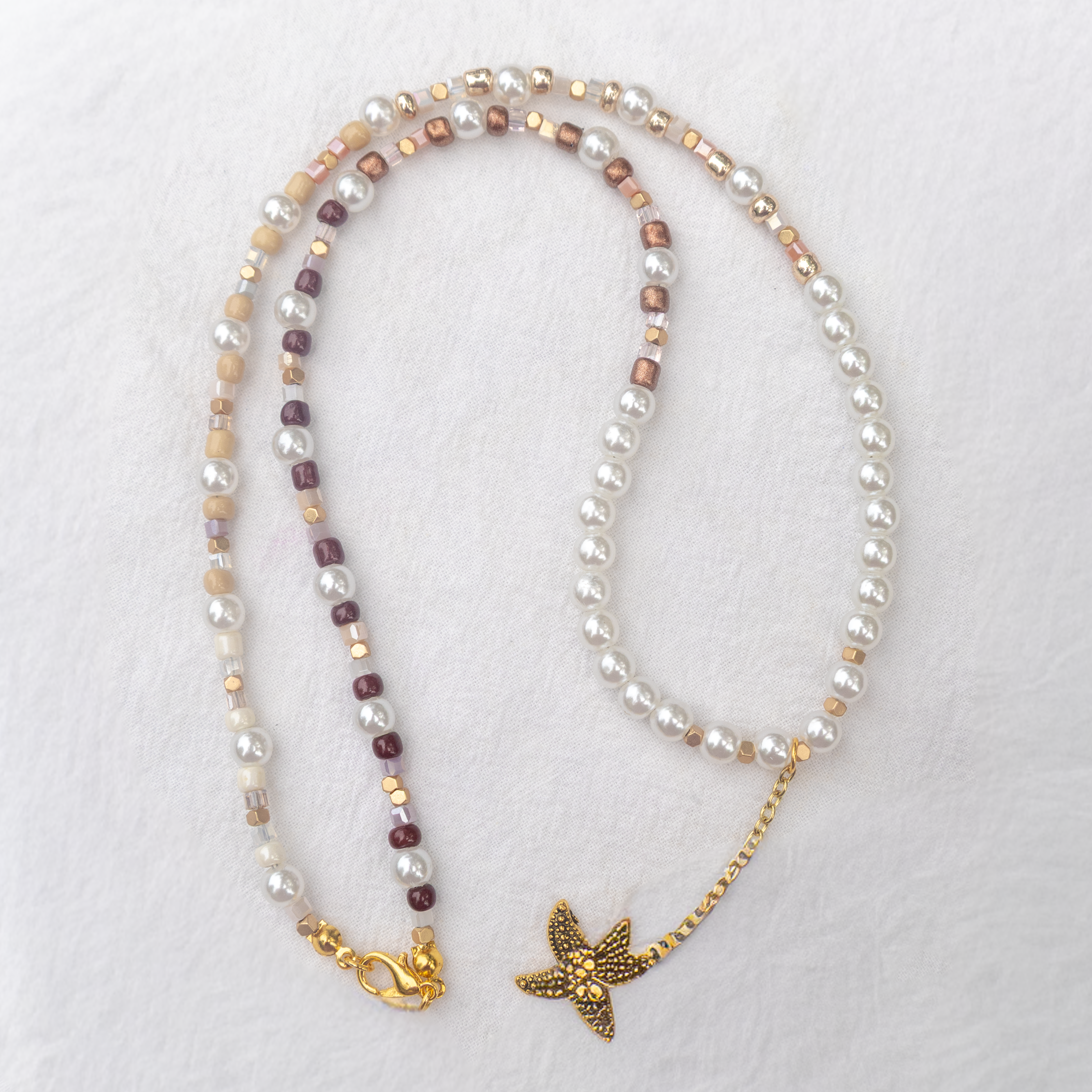 Pearl necklace with starfish pendant on a white background