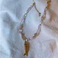 Necklace with a gold fish pendant on a white fabric background